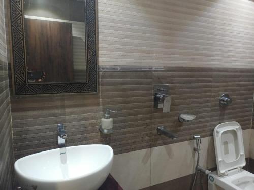 a bathroom with a sink and a mirror and a toilet at The Brahmaputra Hotel in Dhuburi