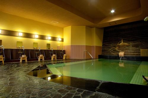 a pool in the middle of a room with chairs at Yuyado Ichibanchi in Atami
