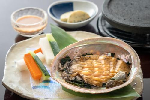a bowl of food on a plate with vegetables and sauce at Yuyado Ichibanchi in Atami