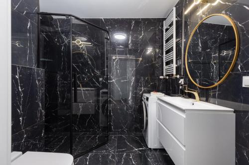 a bathroom with black marble walls and a round mirror at Exclusive Apartment Różana with AC & Balcony View 1 km to the Beach by Renters in Sianozety