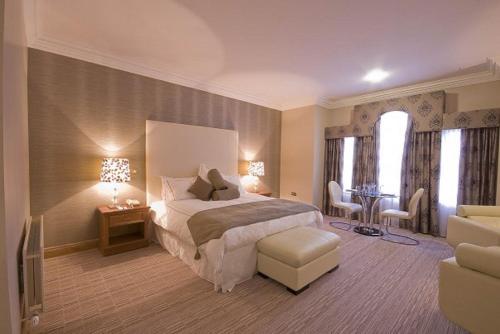 um quarto com uma cama, uma mesa e cadeiras em Lady Gregory Hotel, Leisure Club & Beauty Rooms em Gort