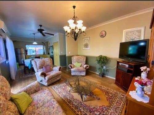 ein Wohnzimmer mit einem Sofa, Stühlen und einem TV in der Unterkunft GOLDEN LACE B&B in Sarina
