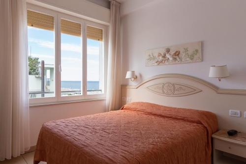a bedroom with a bed with a view of the ocean at Hotel Mocambo in Milano Marittima