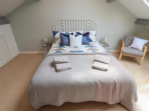 een slaapkamer met een groot bed met blauwe kussens en een stoel bij Ribble Cottage in Settle