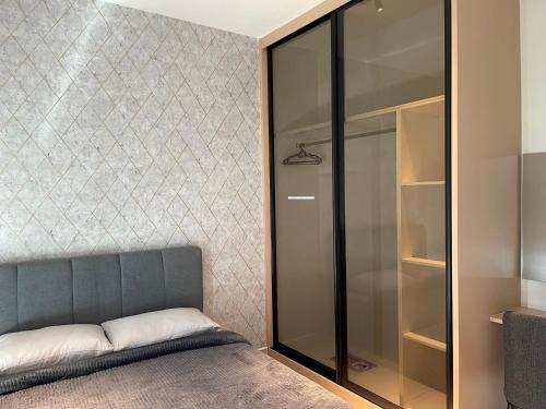 a bedroom with a bed and a glass closet at One Majestic Ipoh - 3 Bedroom Apt For Family of 5 in Ipoh