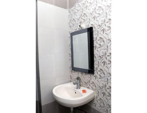 bagno con lavandino e specchio a parete di Hotel Gopi Dham, Haridwar a Haridwār