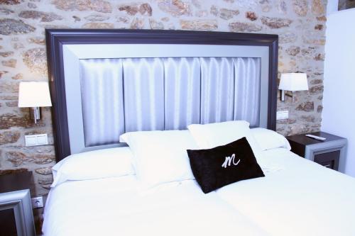 a bedroom with a white bed with a black pillow on it at Hotel Montenegro Compostela in Santiago de Compostela