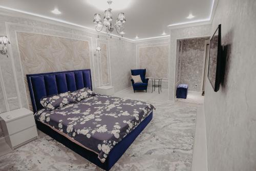a bedroom with a blue bed and a chair at VIP апартаменты однокомнатная квартира in Uralsk