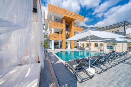 a pool with chairs and umbrellas next to a building at Lupia Suites in Kalkan