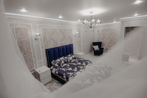 a bedroom with a blue bed and a chair at VIP апартаменты однокомнатная квартира in Uralsk