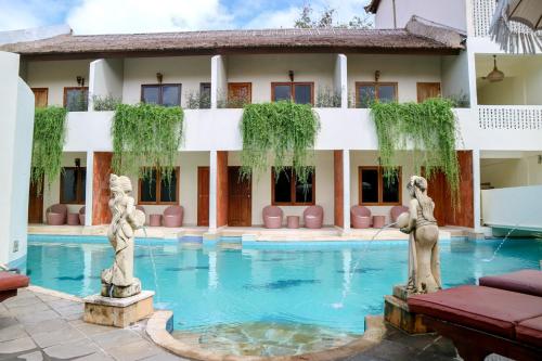 a hotel with a swimming pool with statues in front of it at The Lagoon Bali Pool Hotel and Suites in Legian