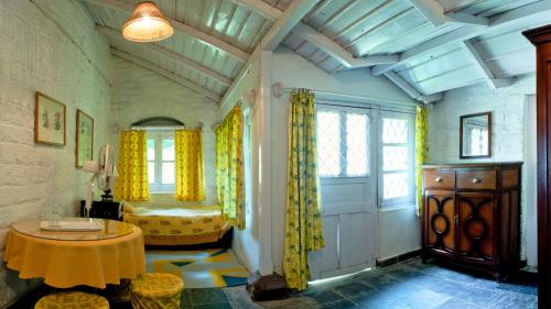 a living room with a table and yellow curtains at Neemrana's - Ramgarh Bungalows in Rāmgarh