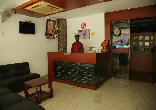 un hombre parado en un mostrador en una sala de espera en Hotel seasons, en Pondicherry