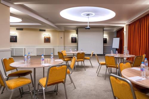 a conference room with tables and chairs and a whiteboard at GINGER Hotel in Tbilisi City