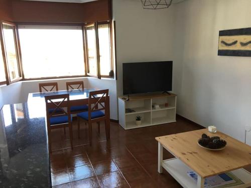 a living room with a table and a television at Apartamento Playa de Usil in Mogro