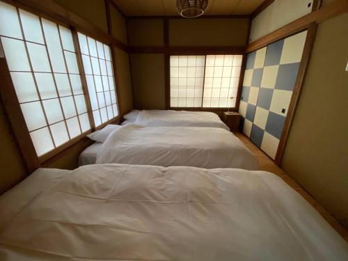 three beds in a room with three windows at ＡＴＴＡ ＨＯＴＥＬ ＫＡＭＡＫＵＲＡ / Vacation STAY 77545 in Kamakura