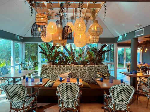 ein Esszimmer mit Tischen, Stühlen und Kronleuchtern in der Unterkunft Broadwater Resort WA Tourism Awards 2022 Gold Winner in Busselton