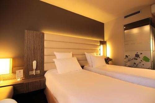two beds in a hotel room with white sheets at Hôtel de Brienne in Toulouse
