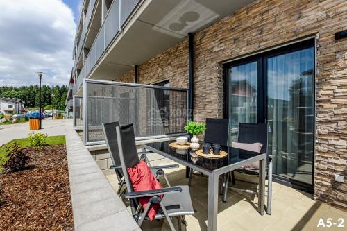 a patio with a table and chairs in front of a building at KORZO LIPNO 2 in Lipno nad Vltavou