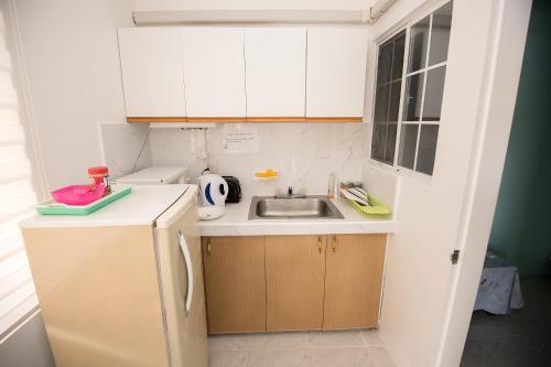 a small kitchen with white cabinets and a sink at Daora guesthouse in Garapan
