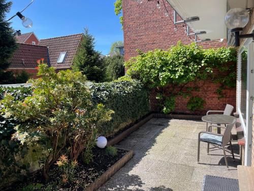 a garden with a table and chairs and a brick wall at Ferienwohnung Mühlenwarf in Emden