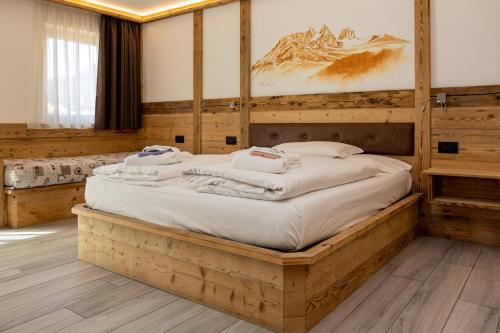 ein Schlafzimmer mit einem großen Bett mit einem Holzrahmen in der Unterkunft Wellness Hotel Dolomia in Soraga