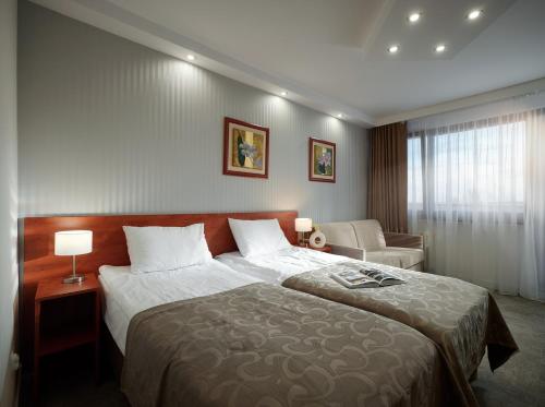 ein Hotelzimmer mit einem großen Bett und einem Stuhl in der Unterkunft Arka Medical Spa in Kołobrzeg