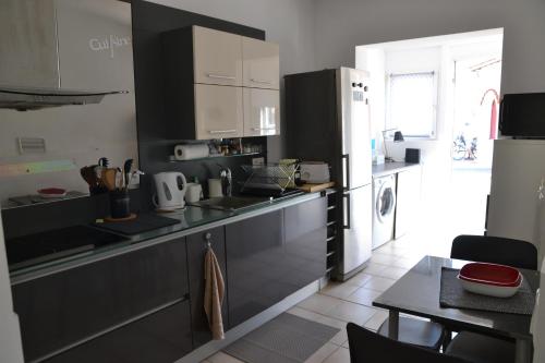 une cuisine avec des appareils en noir et blanc et une table dans l'établissement Joli appartement avec jardin, rive droite, à Palavas-les-Flots