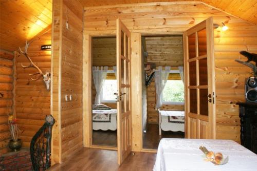 a wooden room with a bed and two windows at Akmeninė Sala in Šventoji