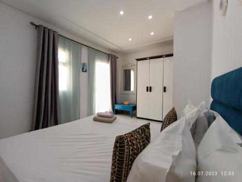 a bedroom with a large white bed with two chairs at Residence Debbabi in Monastir