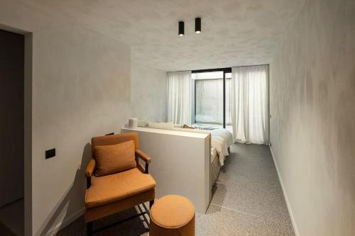 um quarto com uma cama, uma cadeira e uma janela em Ter Heyde Walle em Koekelare