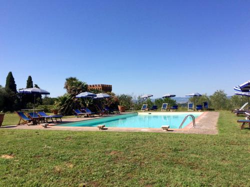 a swimming pool in a yard with chairs and umbrellas at Agriturismo La Palazzina in Palaia