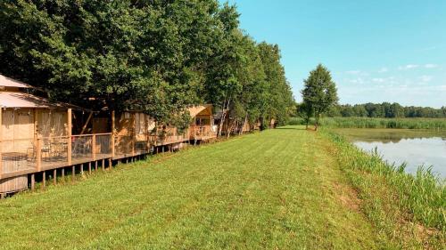 a row of houses on the side of a river at Zatoria Luxury Glamping ZATOR in Zator