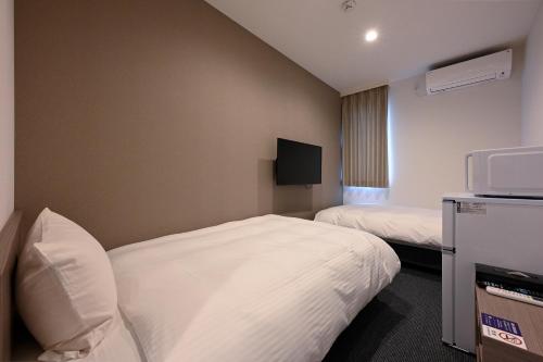 a hotel room with two beds and a tv at HOTEL R9 The Yard Ashikagafukutomi in Ashikaga