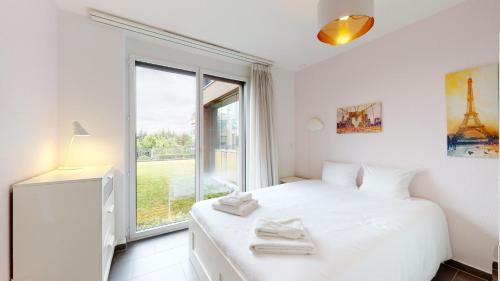 a white bedroom with a bed and a window at Modern flat with beautiful outdoor space in Le Mont-sur-Lausanne