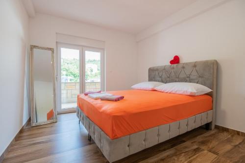 a bedroom with a bed with an orange blanket at Luxury Apartment Budimir in Imotski