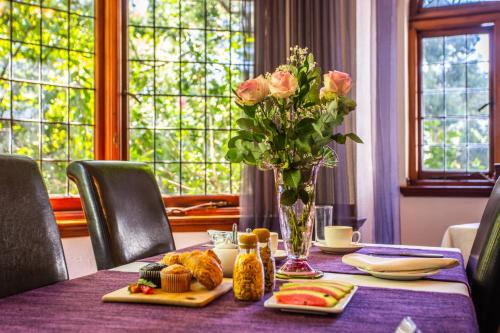 a table with a vase of flowers and food on it at Cape Riviera Guesthouse in Cape Town