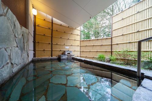 a swimming pool in the middle of a house with a wall at Gora Hotel Paipuno Kemuri Plus in Hakone