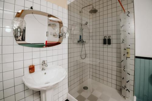 a white bathroom with a sink and a shower at Le Cap 80… La suite des nostalgiques in Gujan-Mestras