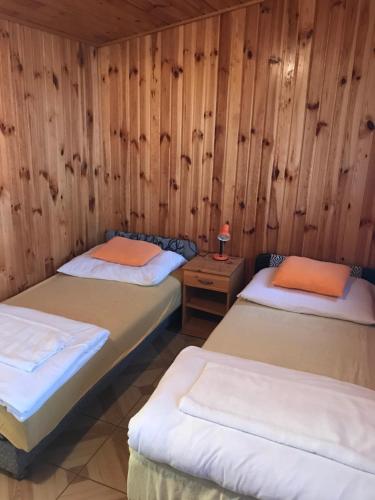 two beds in a room with wooden walls at Cuki lak in Kiszombor