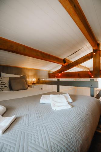 Cette chambre dispose d'un grand lit blanc et de plafonds en bois. dans l'établissement La Cabane du Littoral, SPA et nature chez Ivona Vacances, au Teich