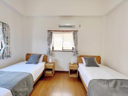 two twin beds in a room with a window at 千間川-緑橋 in Osaka