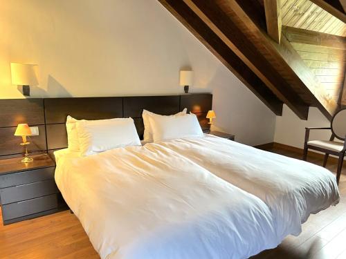 a bedroom with a large white bed with two lamps at Dúplex amb encant al casc antic d'Esterri i vistes úniques by RURAL D'ÀNEU in Esterri d'Àneu