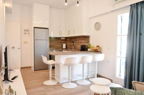 a kitchen with white cabinets and a counter with stools at ΙΖΑΜΠΩ II in Kalamata