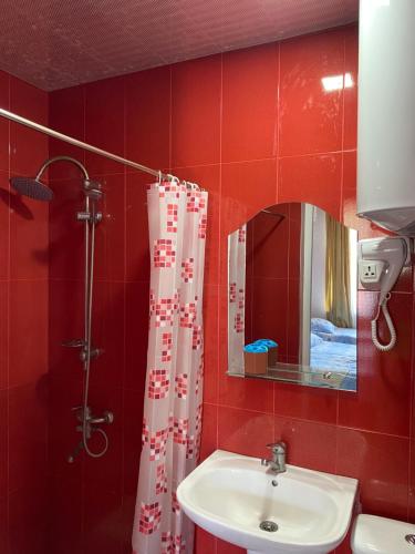 baño rojo con lavabo y ducha en Hotel Aurora en Ureki