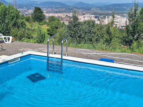 a large blue swimming pool with a view of a city at Bungalovi Lana in Sarajevo