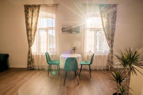 een tafel en stoelen in een kamer met ramen bij Dēseles dzirnavas - Guest House in Embūte