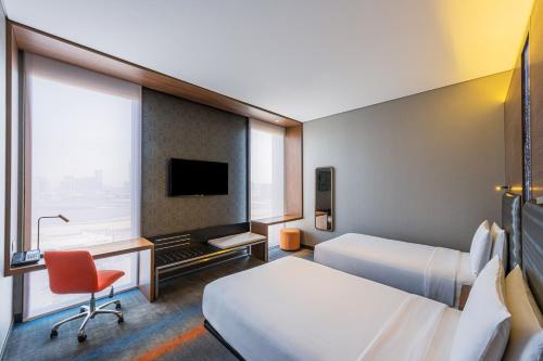 um quarto de hotel com duas camas e uma secretária e uma televisão em Aloft Me'aisam, Dubai em Dubai