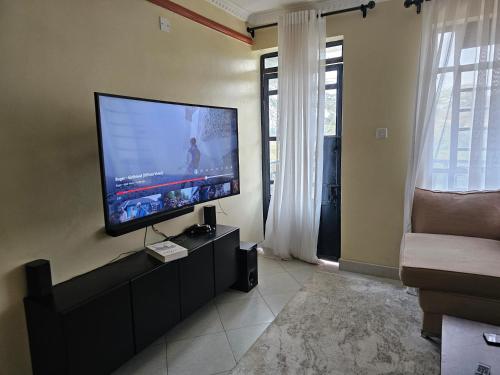 ein Wohnzimmer mit einem Flachbild-TV an der Wand in der Unterkunft Ngomg in Nairobi