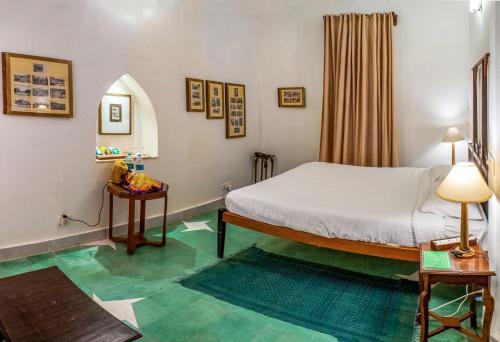 a bedroom with a bed and a green floor at Neemrana's - Tijara Fort Palace in Alwar